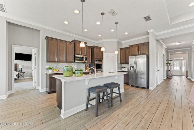 kitchen featuring light countertops, light wood-type flooring, visible vents, and stainless steel appliances