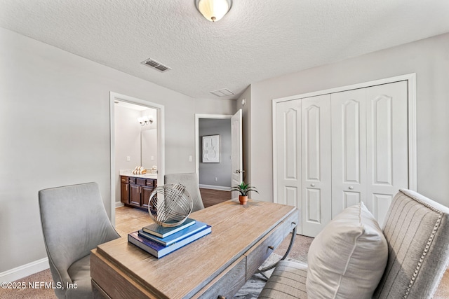 office with baseboards, visible vents, and a textured ceiling