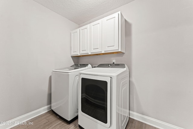 laundry area featuring washer and dryer, baseboards, cabinet space, and a textured ceiling