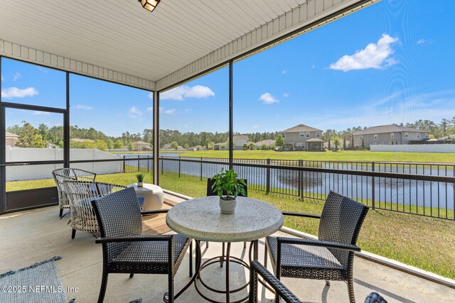 sunroom / solarium with a residential view and a water view