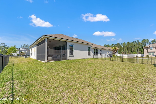 rear view of property featuring a lawn, a fenced backyard, and a sunroom