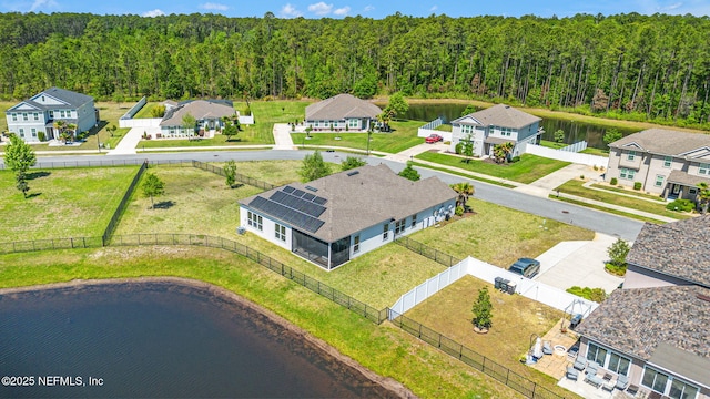 drone / aerial view with a residential view, a view of trees, and a water view
