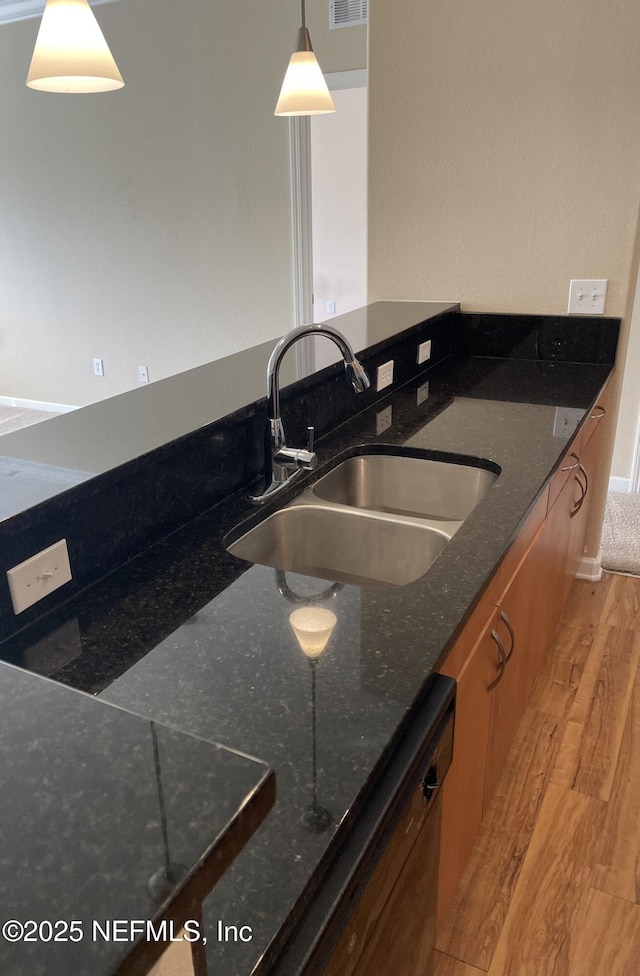 8290 Gate Pkwy W Unit 504, Jacksonville, FL 32216 - kitchen with decorative light fixtures, dark stone counters, a sink, light wood-style floors, and visible vents