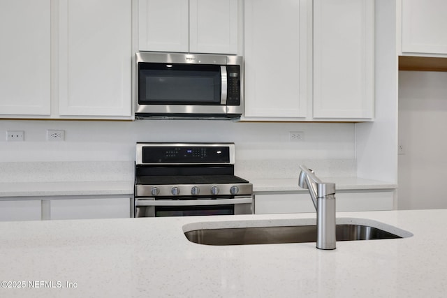 356 Salazar St, Saint Augustine, FL 32095 - kitchen featuring appliances with stainless steel finishes, white cabinets, and light stone countertops