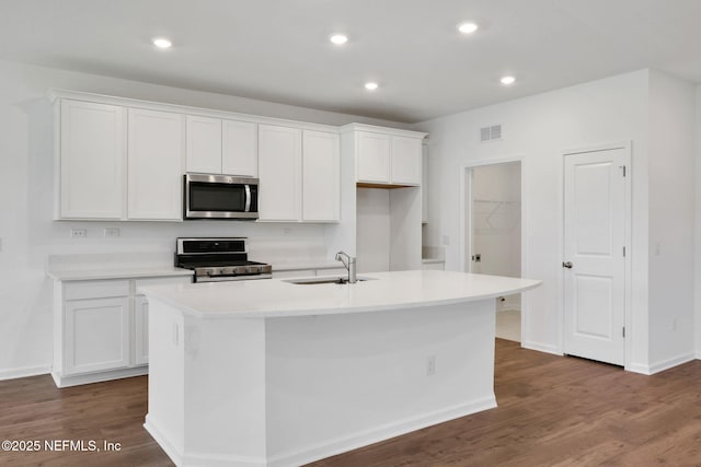 356 Salazar St, Saint Augustine, FL 32095 - kitchen with stainless steel appliances, white cabinets, a center island with sink, light countertops, and dark wood-style floors