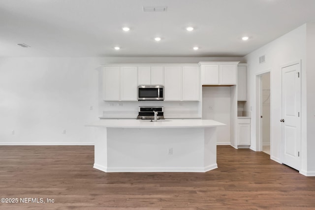 356 Salazar St, Saint Augustine, FL 32095 - kitchen featuring stainless steel microwave, white cabinetry, wood finished floors, an island with sink, and stove