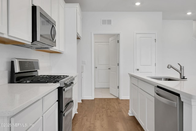 356 Salazar St, Saint Augustine, FL 32095 - kitchen featuring stainless steel appliances, white cabinets, light wood-style floors, recessed lighting, and light stone counters