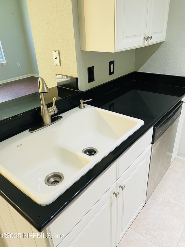 8539 Gate Pkwy W Unit 1616, Jacksonville, FL 32216 - kitchen featuring a sink, dishwasher, light tile patterned floors, dark countertops, and white cabinets