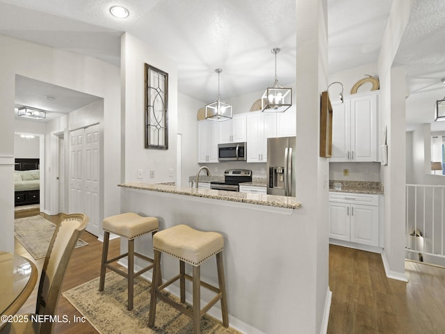35211 Harbour Vista Cir, Saint Augustine, FL 32080 - kitchen featuring white cabinets, appliances with stainless steel finishes, a breakfast bar, and light stone countertops