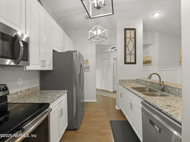 35211 Harbour Vista Cir, Saint Augustine, FL 32080 - kitchen featuring light stone countertops, white cabinetry, wood finished floors, a sink, and stainless steel appliances