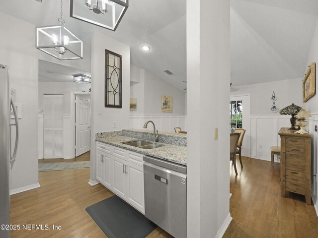 35211 Harbour Vista Cir, Saint Augustine, FL 32080 - kitchen featuring appliances with stainless steel finishes, wood finished floors, a sink, light stone counters, and lofted ceiling