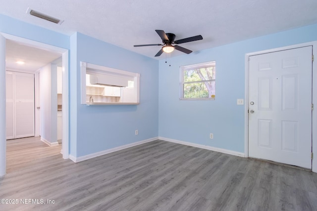 empty room with visible vents, ceiling fan, wood finished floors, and baseboards