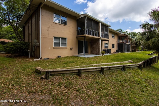 back of property with a patio area, a sunroom, and a lawn