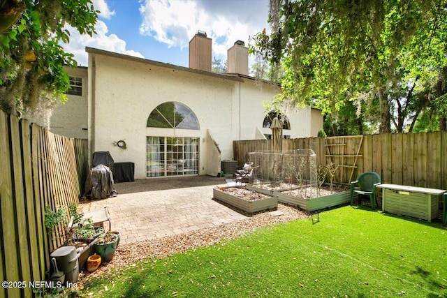 1216 Radis Pl, Jacksonville, FL 32225 - back of property with a fenced backyard, a vegetable garden, stucco siding, a yard, and a patio area