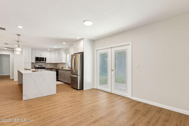 kitchen with light wood finished floors, white cabinets, appliances with stainless steel finishes, and baseboards