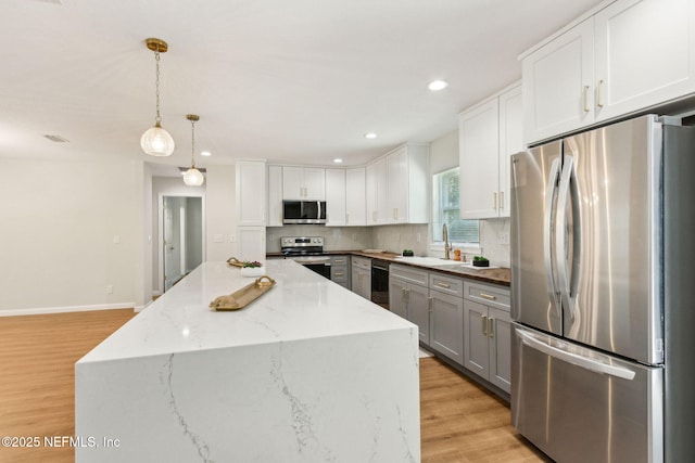 kitchen with gray cabinets, light wood-style flooring, stainless steel appliances, white cabinets, and a sink