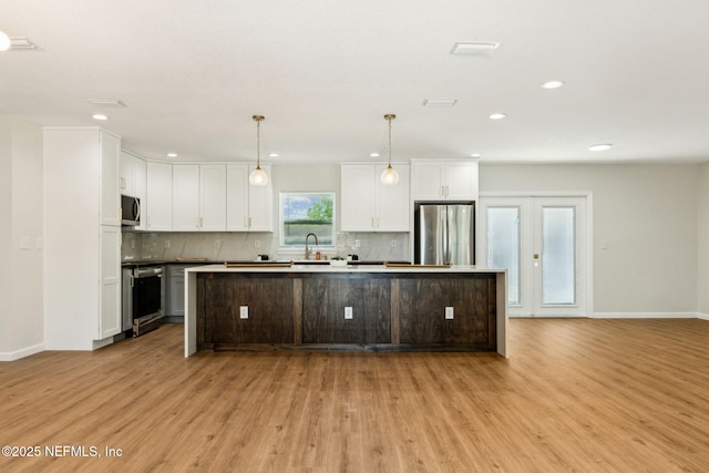 kitchen with white cabinetry, tasteful backsplash, light wood-style floors, stainless steel appliances, and a center island