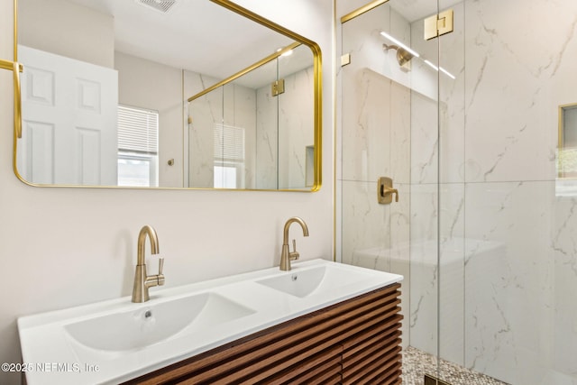 bathroom featuring a marble finish shower, a sink, double vanity, and visible vents