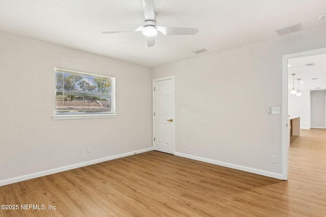 spare room with baseboards, light wood-type flooring, visible vents, and a ceiling fan