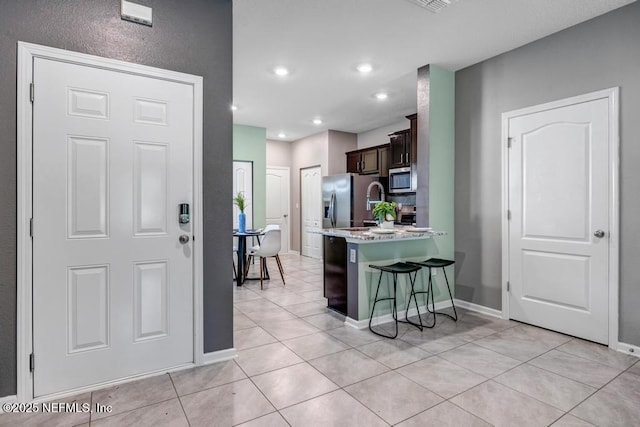 234 Aralia Ln, Jacksonville, FL 32216 - kitchen with appliances with stainless steel finishes, a breakfast bar area, light countertops, light tile patterned floors, and a peninsula