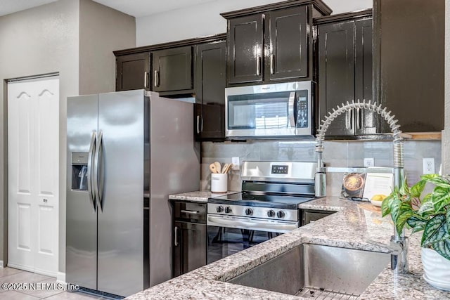 234 Aralia Ln, Jacksonville, FL 32216 - kitchen with appliances with stainless steel finishes, light stone counters, tasteful backsplash, and light tile patterned floors