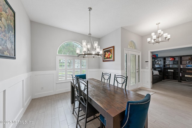 dining space featuring light wood-style flooring, a chandelier, and wainscoting