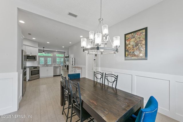 dining room with visible vents, a notable chandelier, light wood-style floors, recessed lighting, and wainscoting