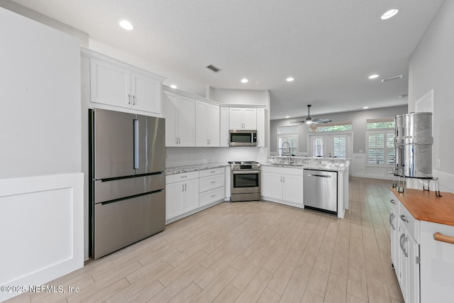 kitchen featuring a peninsula, a ceiling fan, visible vents, appliances with stainless steel finishes, and a sink