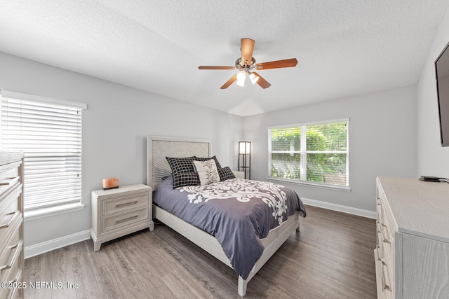 bedroom featuring baseboards, a ceiling fan, light wood-style floors, and a textured ceiling
