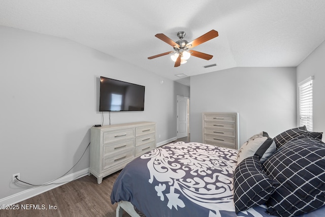 bedroom featuring wood finished floors, baseboards, lofted ceiling, and visible vents