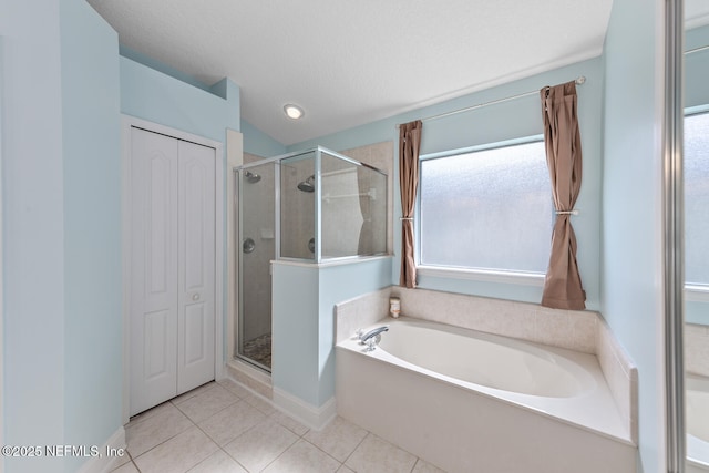 full bathroom featuring a closet, tile patterned flooring, a stall shower, and a garden tub