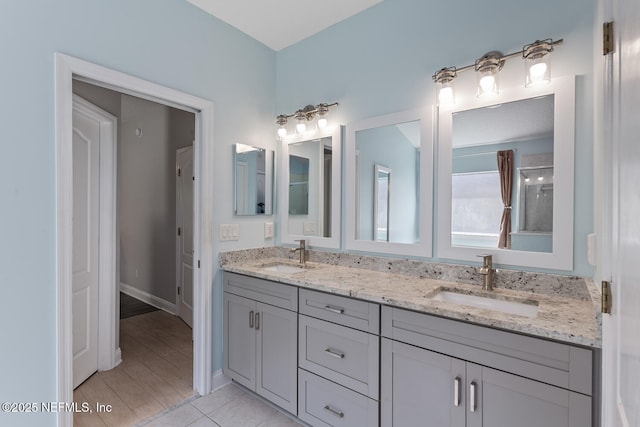 full bathroom with a sink, tile patterned floors, baseboards, and double vanity