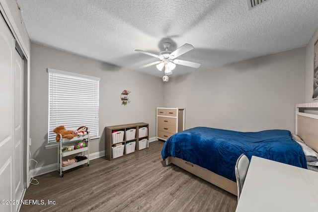 bedroom featuring a closet, baseboards, ceiling fan, a textured ceiling, and wood finished floors