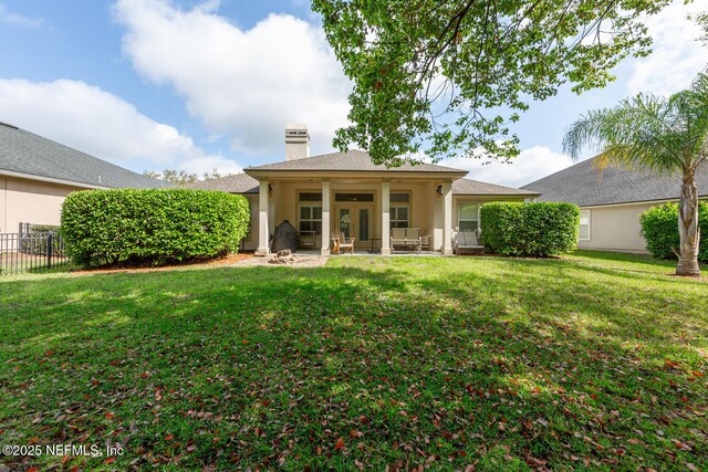 back of property featuring a patio, a chimney, fence, and a yard