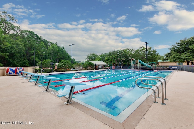 community pool featuring a patio area, fence, and playground community