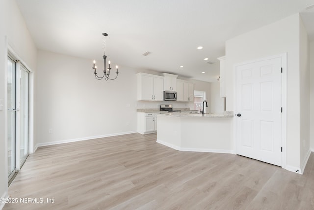 2895 Cross Creek Dr, Green Cove Springs, FL 32043 - kitchen with appliances with stainless steel finishes, white cabinetry, a sink, light wood-type flooring, and a notable chandelier