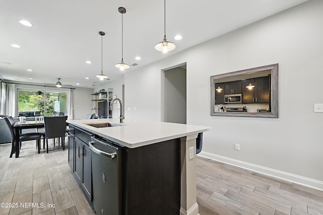kitchen with light wood-style flooring, a sink, recessed lighting, light countertops, and appliances with stainless steel finishes
