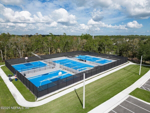 view of swimming pool with a forest view, fence, a yard, and a tennis court