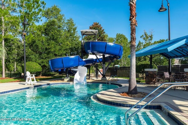 community pool featuring a water slide, fence, and a patio area