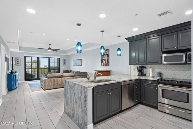 1478 Riverplace Blvd Unit 803, Jacksonville, FL 32207 - kitchen featuring a peninsula, stainless steel appliances, tasteful backsplash, a sink, and a tray ceiling