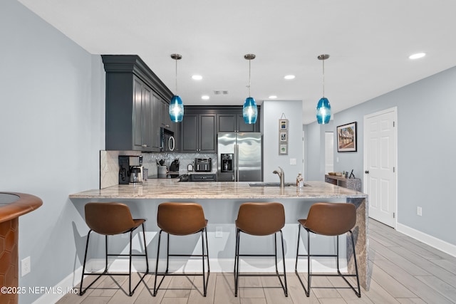 1478 Riverplace Blvd Unit 803, Jacksonville, FL 32207 - kitchen with a peninsula, a breakfast bar, a sink, stainless steel fridge with ice dispenser, and backsplash