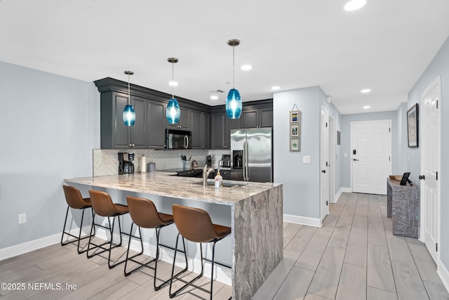 1478 Riverplace Blvd Unit 803, Jacksonville, FL 32207 - kitchen featuring light stone counters, tasteful backsplash, a breakfast bar, appliances with stainless steel finishes, and a peninsula