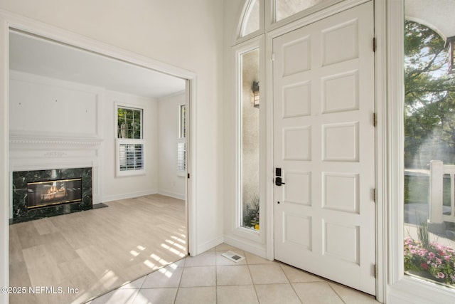 entrance foyer with a fireplace, visible vents, baseboards, and light tile patterned floors