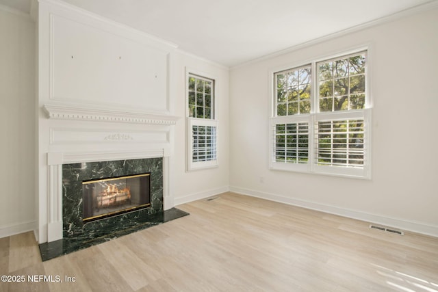 unfurnished living room with wood finished floors, visible vents, a fireplace, and ornamental molding
