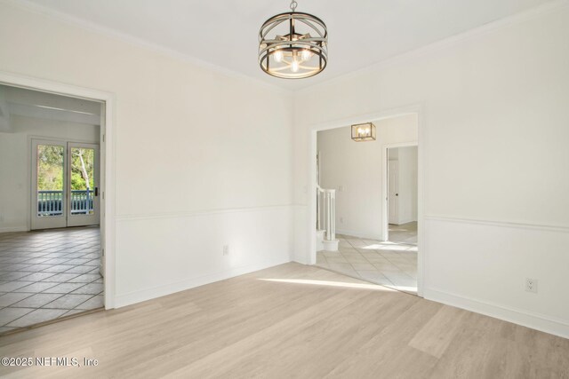 interior space with a chandelier, light wood-style floors, crown molding, and baseboards