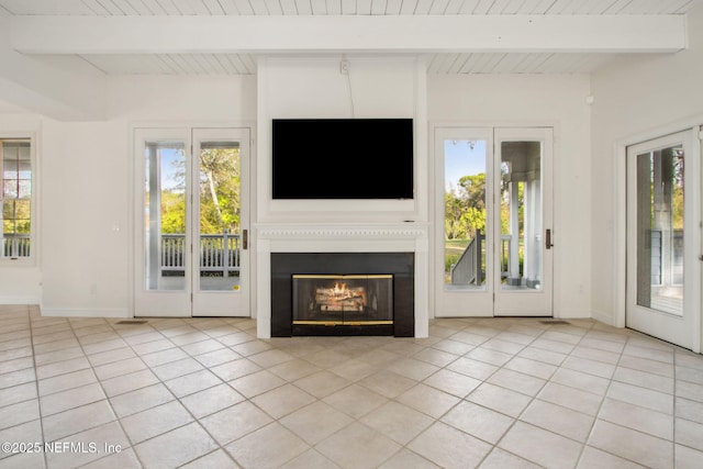 unfurnished living room with beamed ceiling, baseboards, a glass covered fireplace, and light tile patterned floors