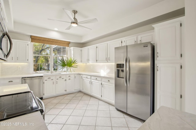 kitchen featuring white cabinets, a sink, backsplash, ceiling fan, and appliances with stainless steel finishes