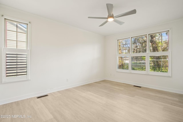 empty room featuring light wood-type flooring, visible vents, ceiling fan, and crown molding