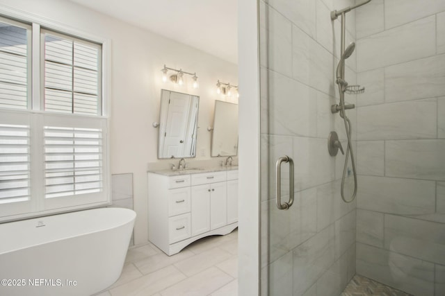 bathroom featuring a wealth of natural light, a shower stall, double vanity, and a freestanding bath