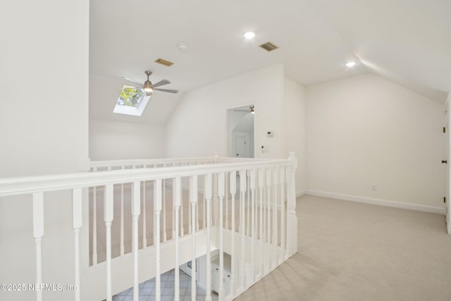 corridor featuring lofted ceiling with skylight, baseboards, carpet, visible vents, and recessed lighting